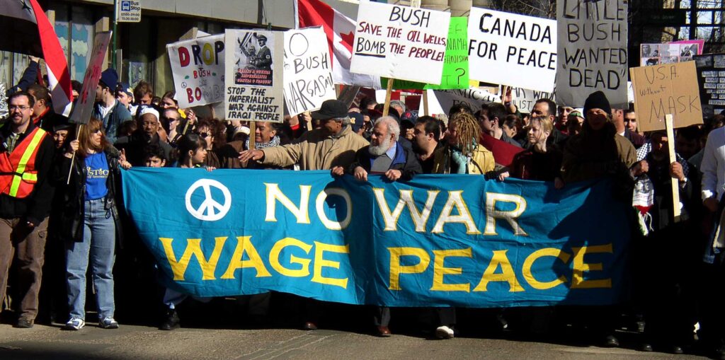 Marchers carrying a No War Wage Peace banner and protest signs during an anti-war demonstration in Edmonton.