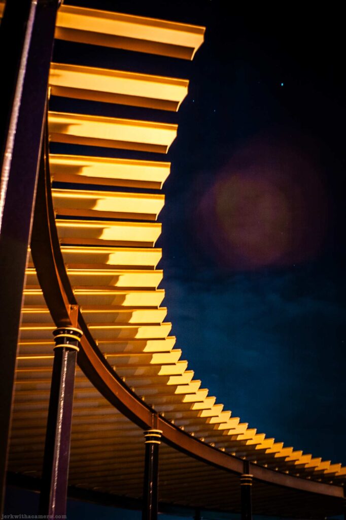 Curved architectural roof structure illuminated against a dark night sky