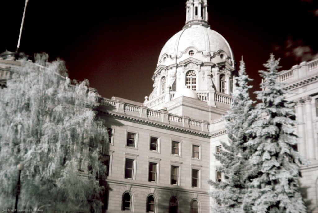 Legislative building with dome and trees photographed in infrared black and white