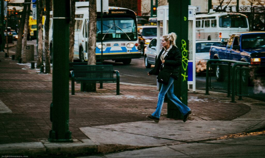 Woman walking near buses and traffic on a city street