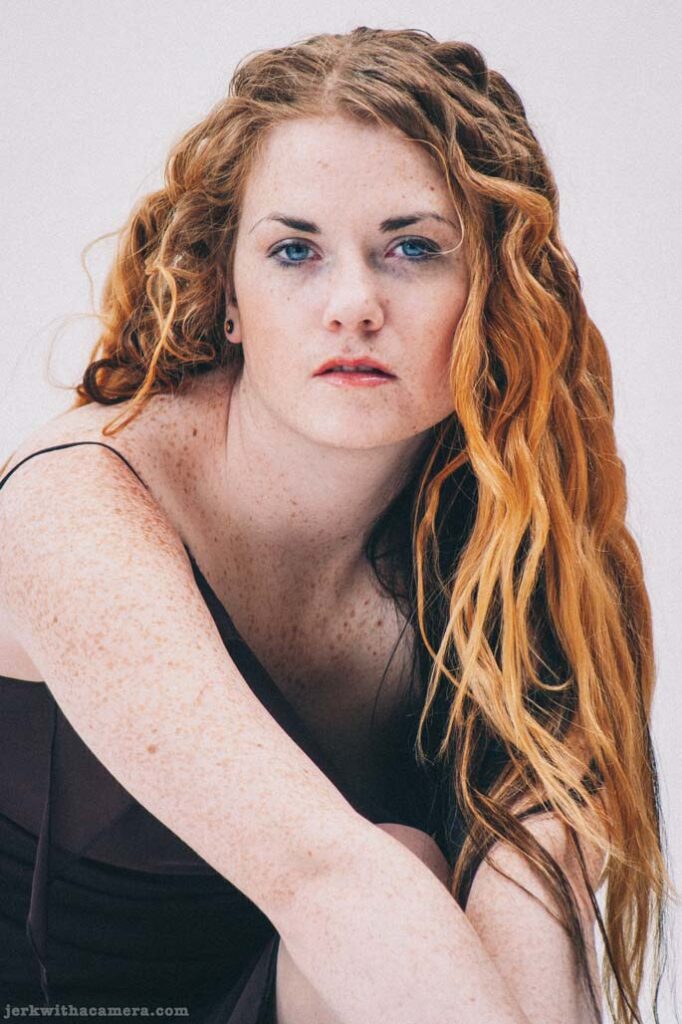 Close portrait of Sommers seated on the floor against a white studio background