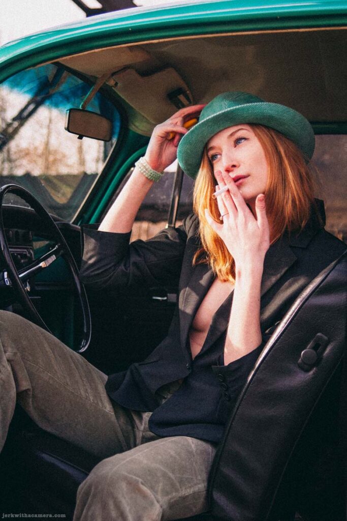 Twilla Coates sitting inside a green Volkswagen Beetle with a cigarette in her hand