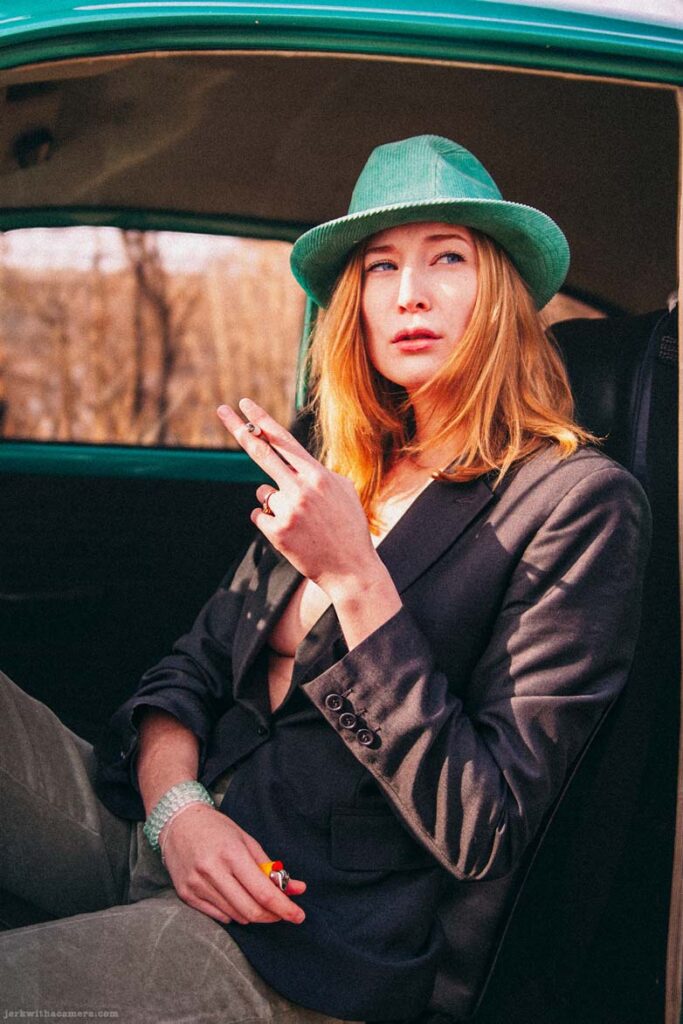 Twilla Coates sitting in the doorway of a Volkswagen Beetle holding a cigarette