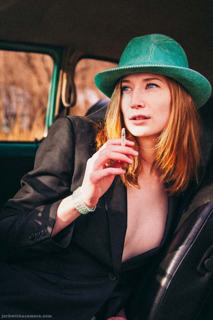 Twilla Coates reclining inside a Volkswagen Beetle holding a cigarette