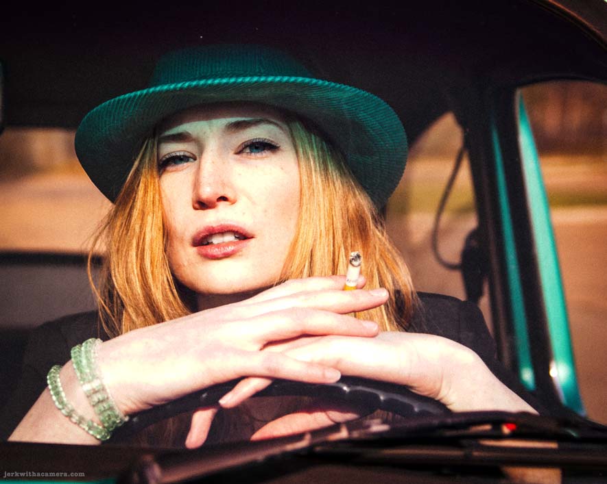 Twilla Coates leaning on the steering wheel of a green Volkswagen Beetle holding a cigarette