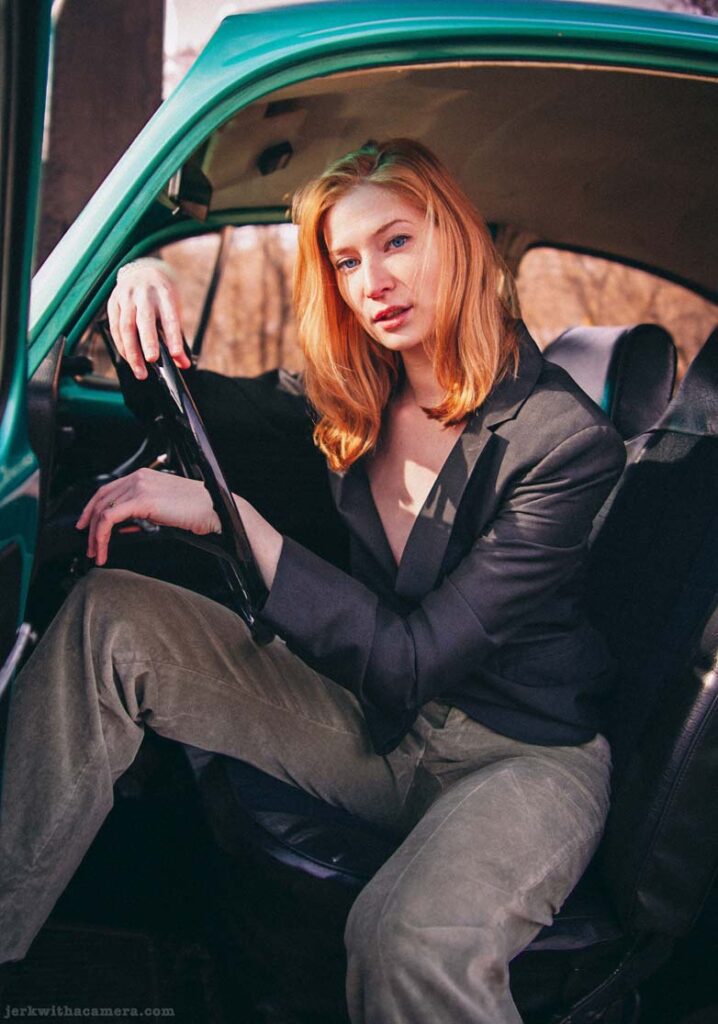 Twilla Coates seated in a Volkswagen Beetle with one arm resting on the steering wheel