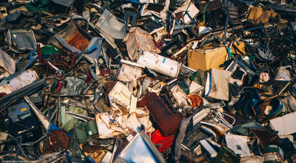 Large pile of crushed metal, appliances, and scrap material at a recycling yard