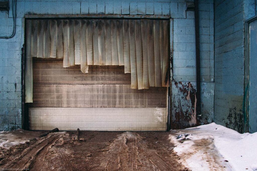 Garage door with hanging curtains and snow-covered ground