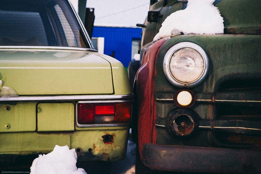 Close view of two parked vintage vehicles with snow