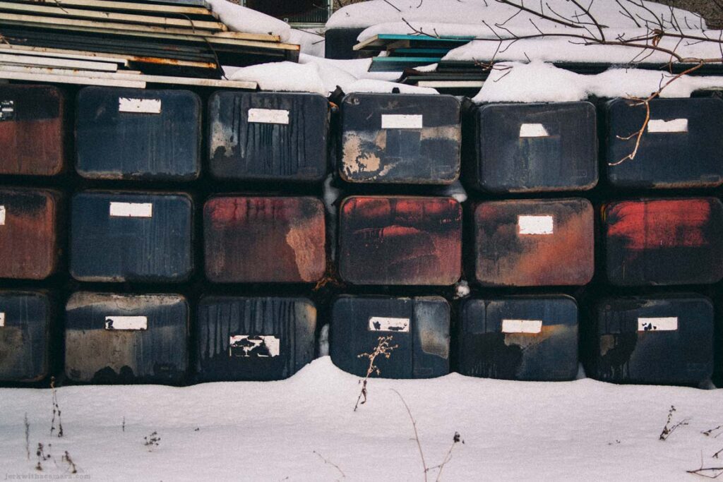 Wide view of stacked plastic containers and snow-covered materials beside a building