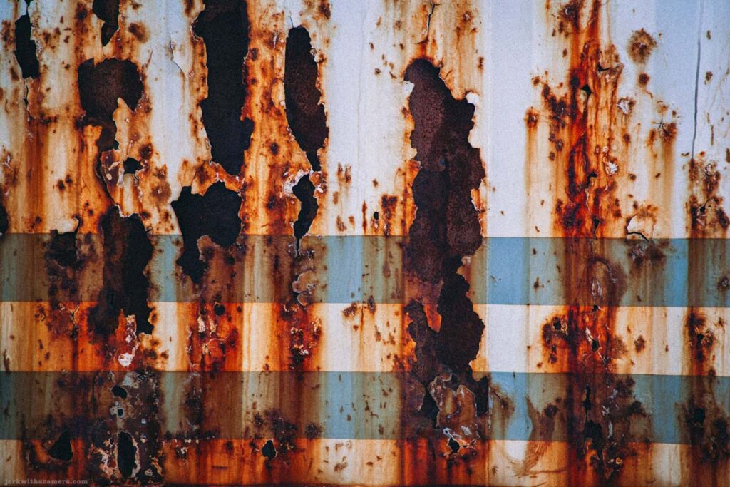 Rusted trailer side with peeling metal and hazard placard