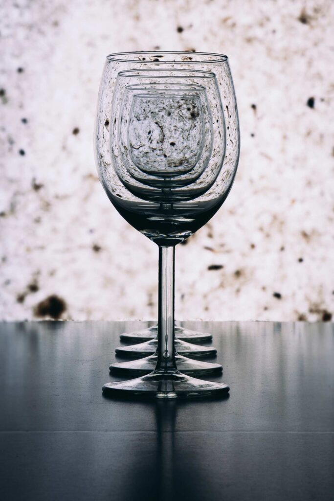 Four wine glasses lined up on a table against a textured white background