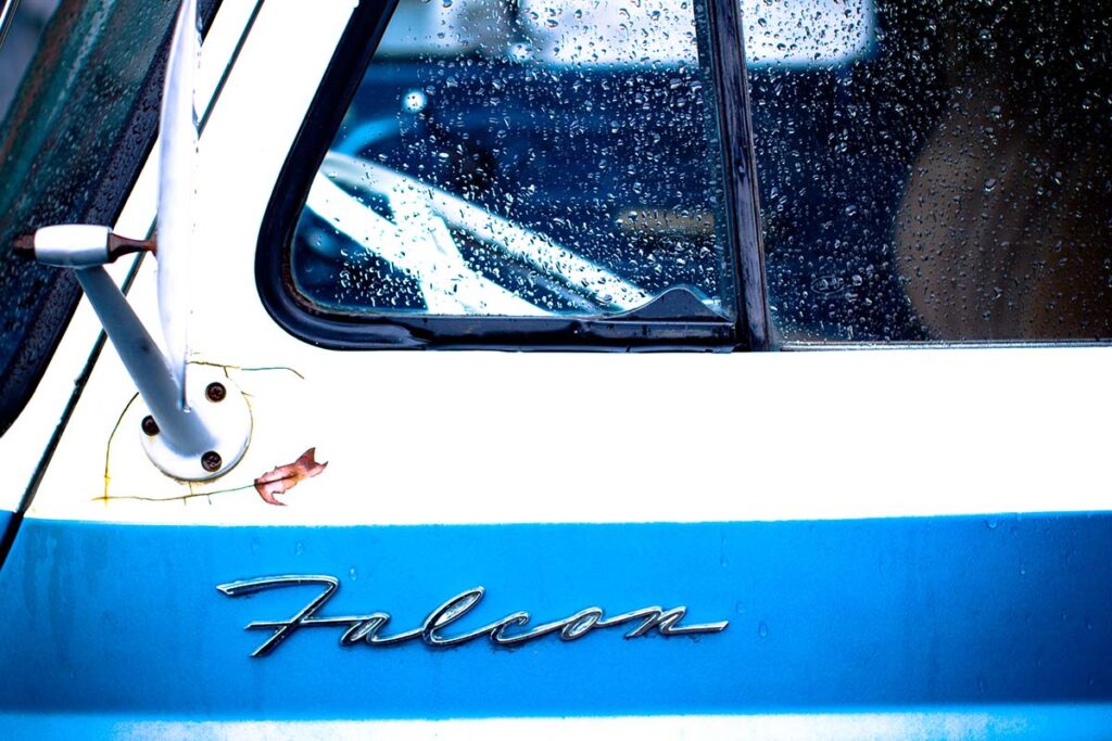 Close-up of a vintage blue Ford truck grille and headlight.