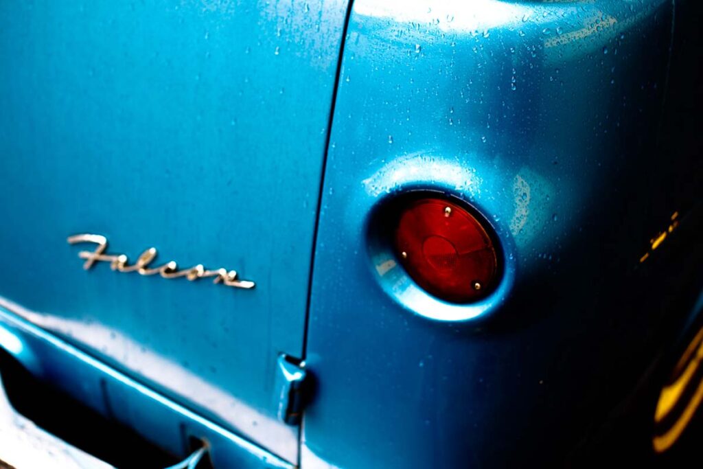 Close-up of a vintage blue Ford truck grille and headlight.