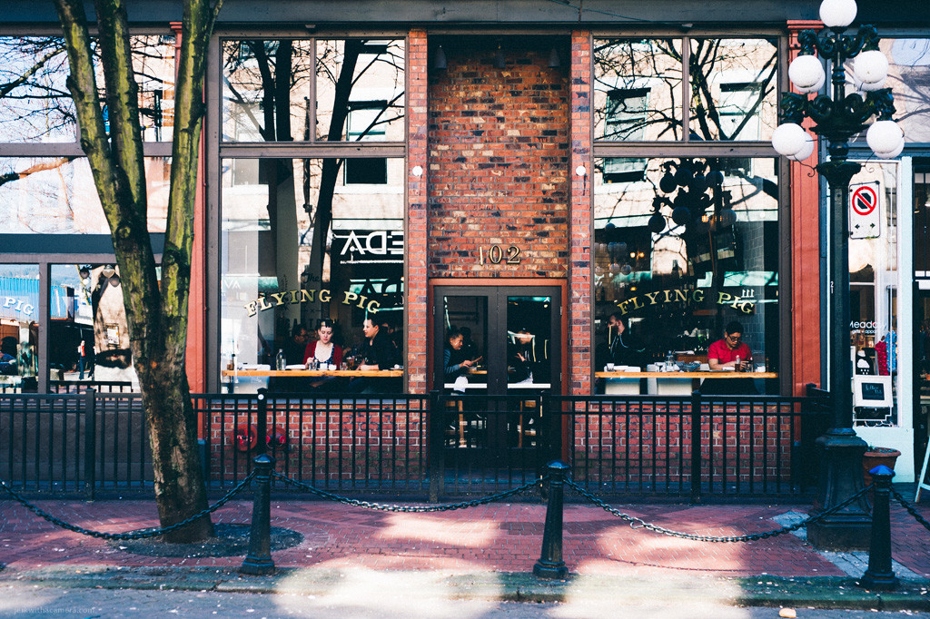 Front entrance of the Flying Pig restaurant with patrons seated inside by the windows.