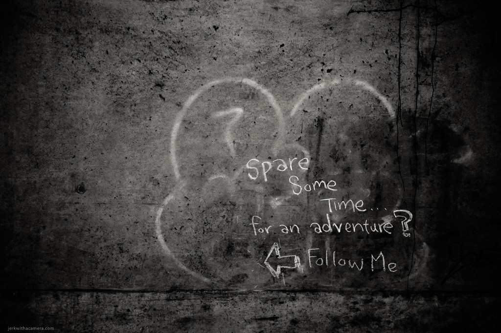 Concrete wall with graffiti text reading Spare Some Time for an adventure? Follow Me and an arrow.