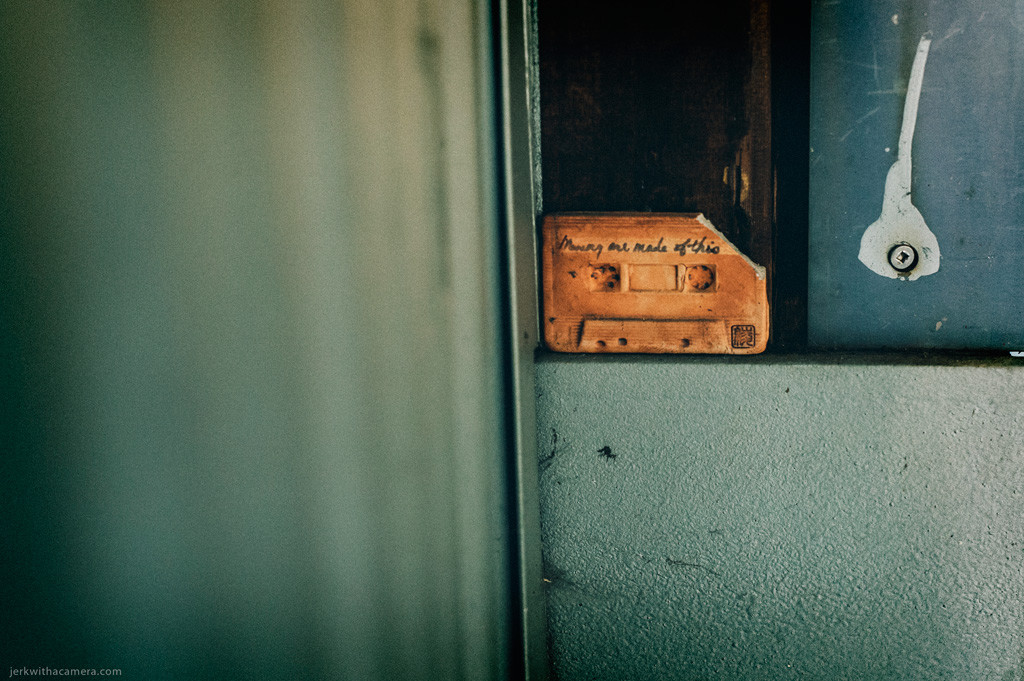 Cassette tape positioned inside an open metal utility box mounted on a concrete surface.