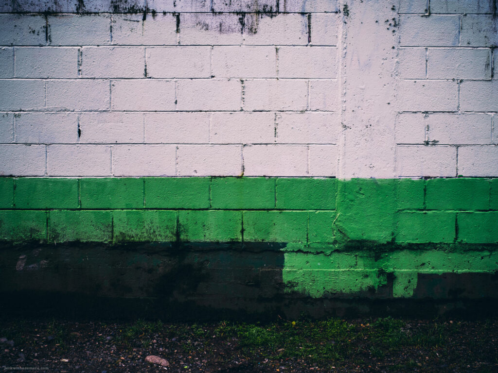 A weathered green and white painted cinderblock wall with stains and grime.