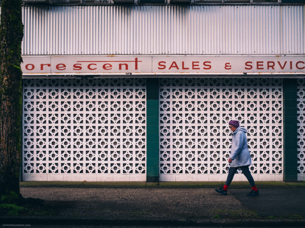 A mid-century modern facade with patterned concrete blocks and a pedestrian walking past.