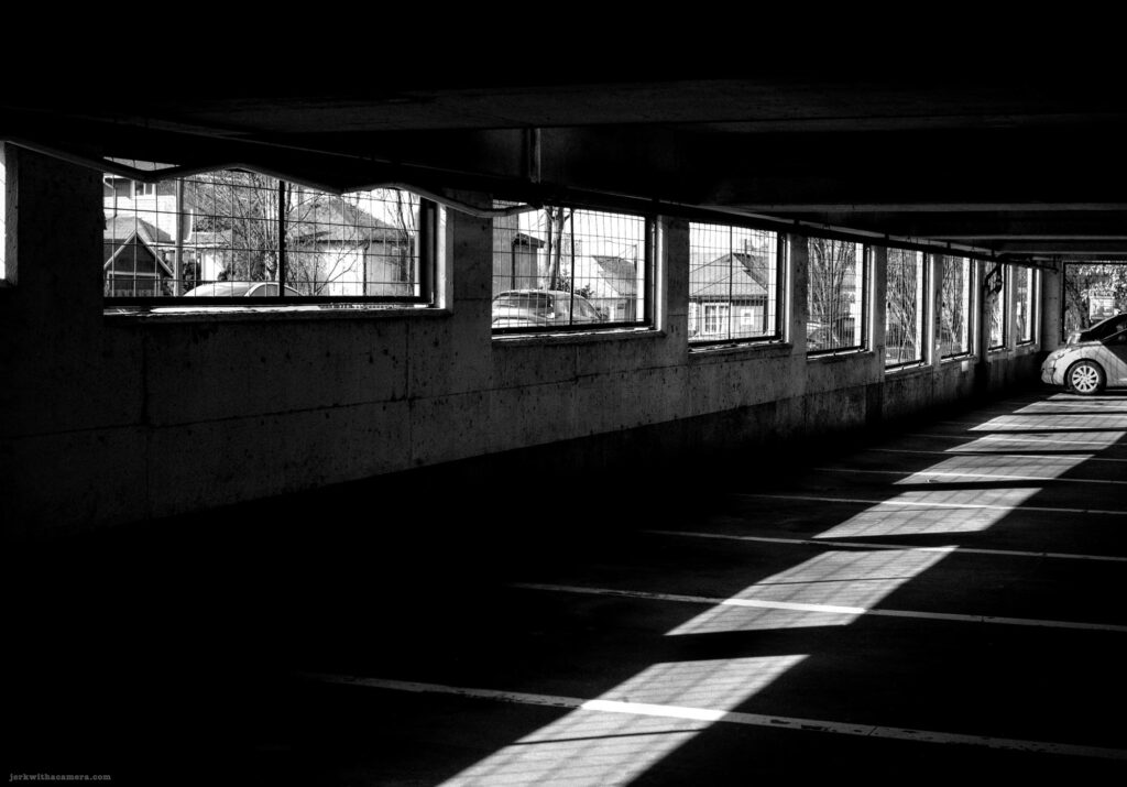 View through garage windows showing houses and a single parked car inside