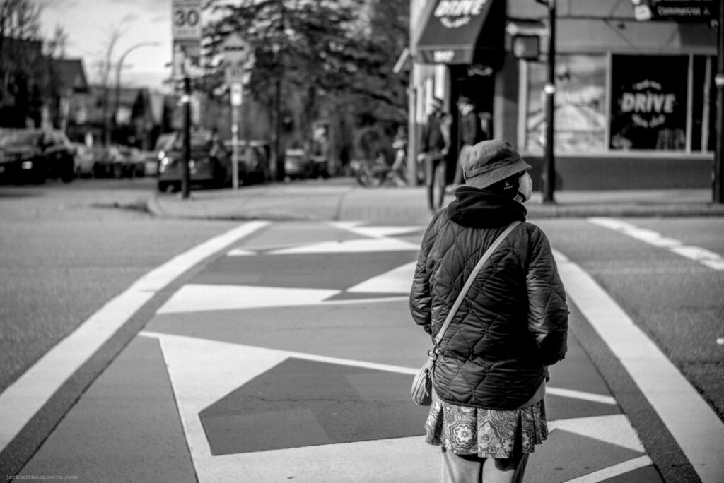 Person in a patterned skirt and bucket hat crossing the street