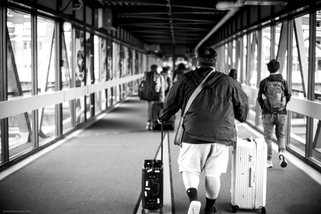 Passengers walking through a terminal walkway with luggage