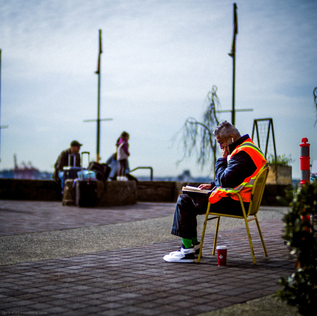 Man in safety vest reading in a chair outdoors, captured with a Leica M-D Typ 262 and the Light Lens Lab 50mm f/1.2 ASPH "1966” lens