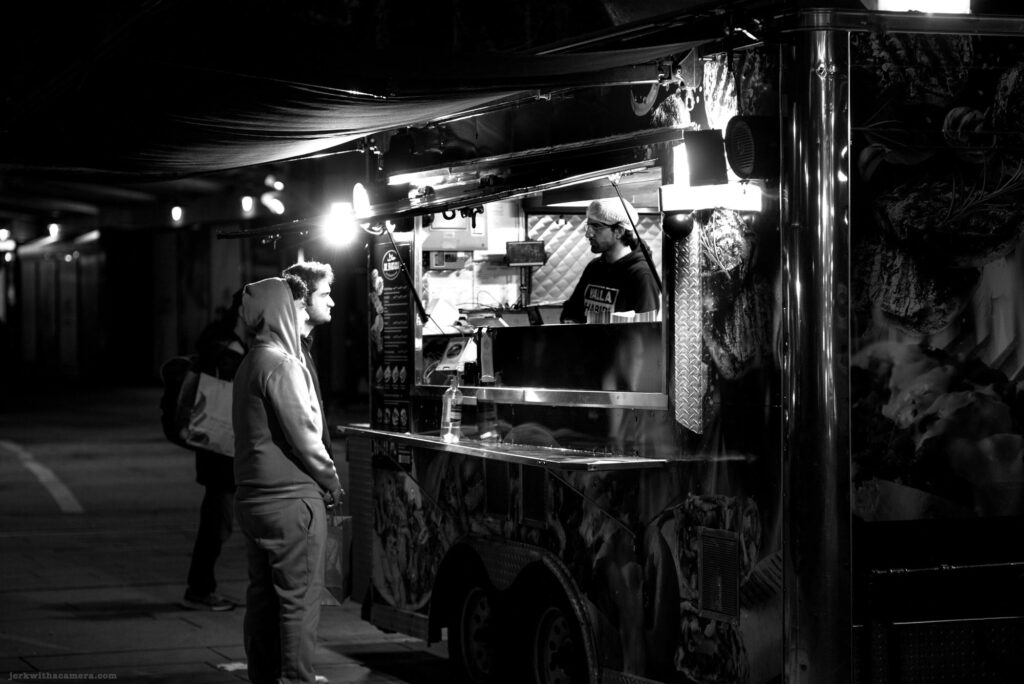 Two men ordering at a food truck at night