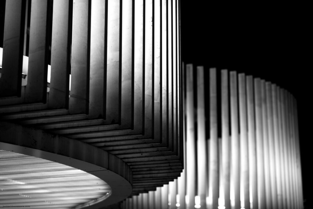 Curved architectural detail with vertical concrete columns lit at night