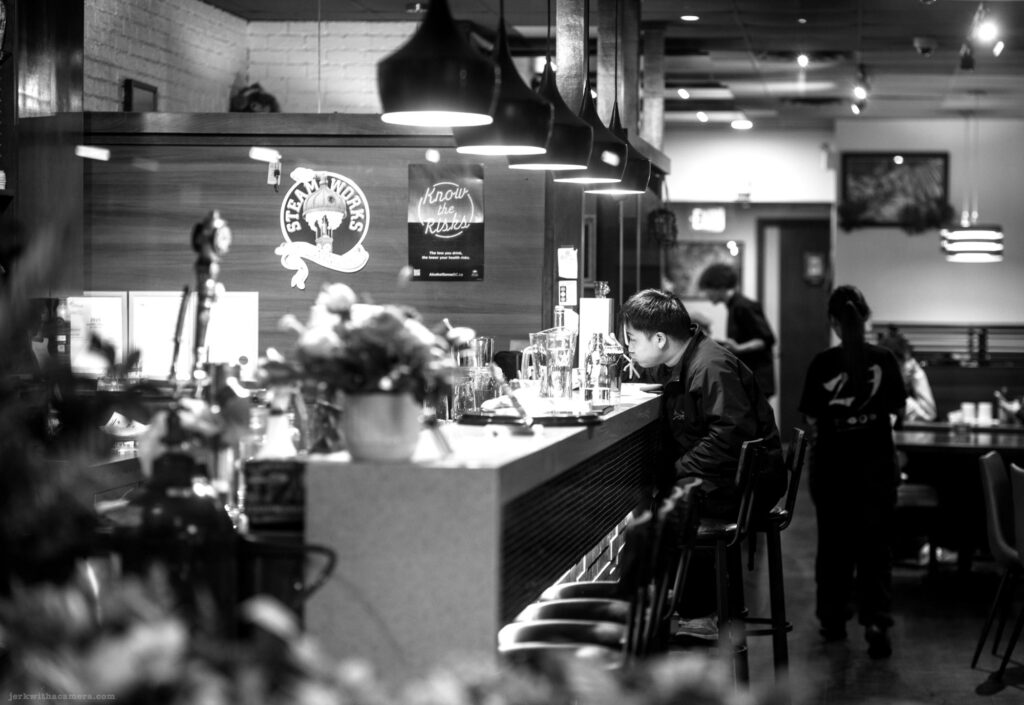 Person sitting at restaurant bar Using chopsticks shot in Black and White at night.