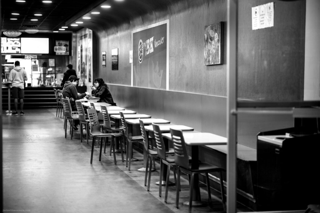 People sitting and talking inside a fast food restaurant shot in Black and White at night.