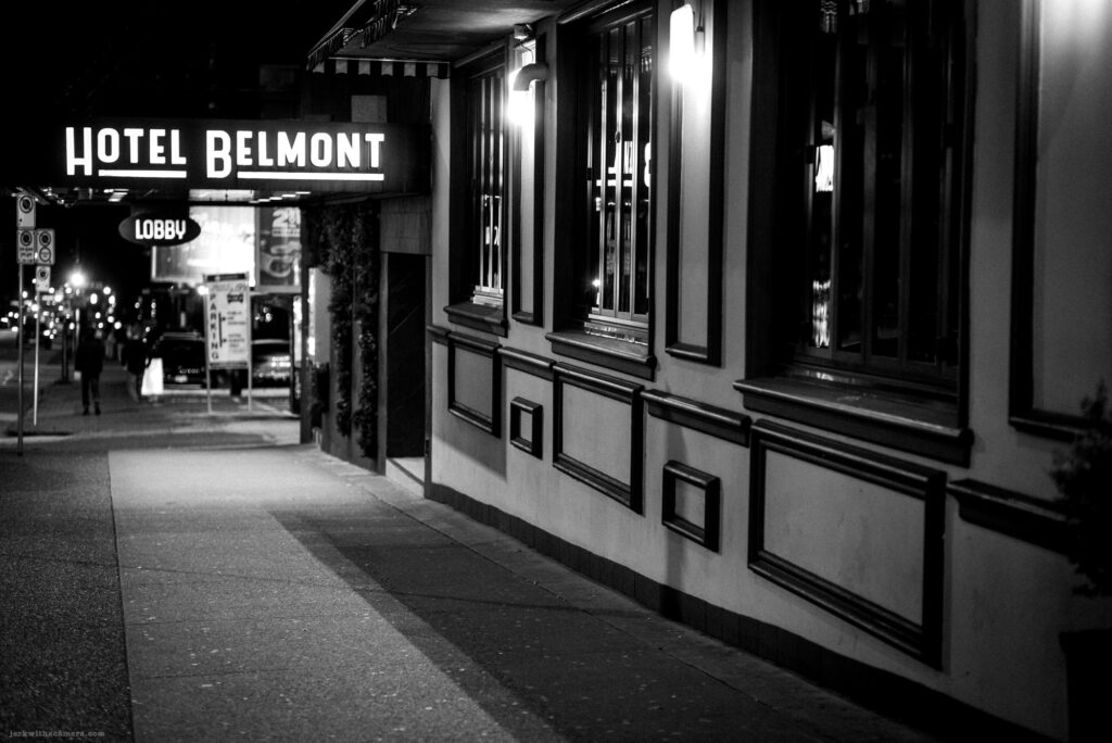 Hotel Belmont sign lit up at night on a quiet downtown sidewalk