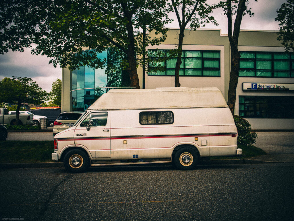 White Dodge RAM van parked in front of office building
