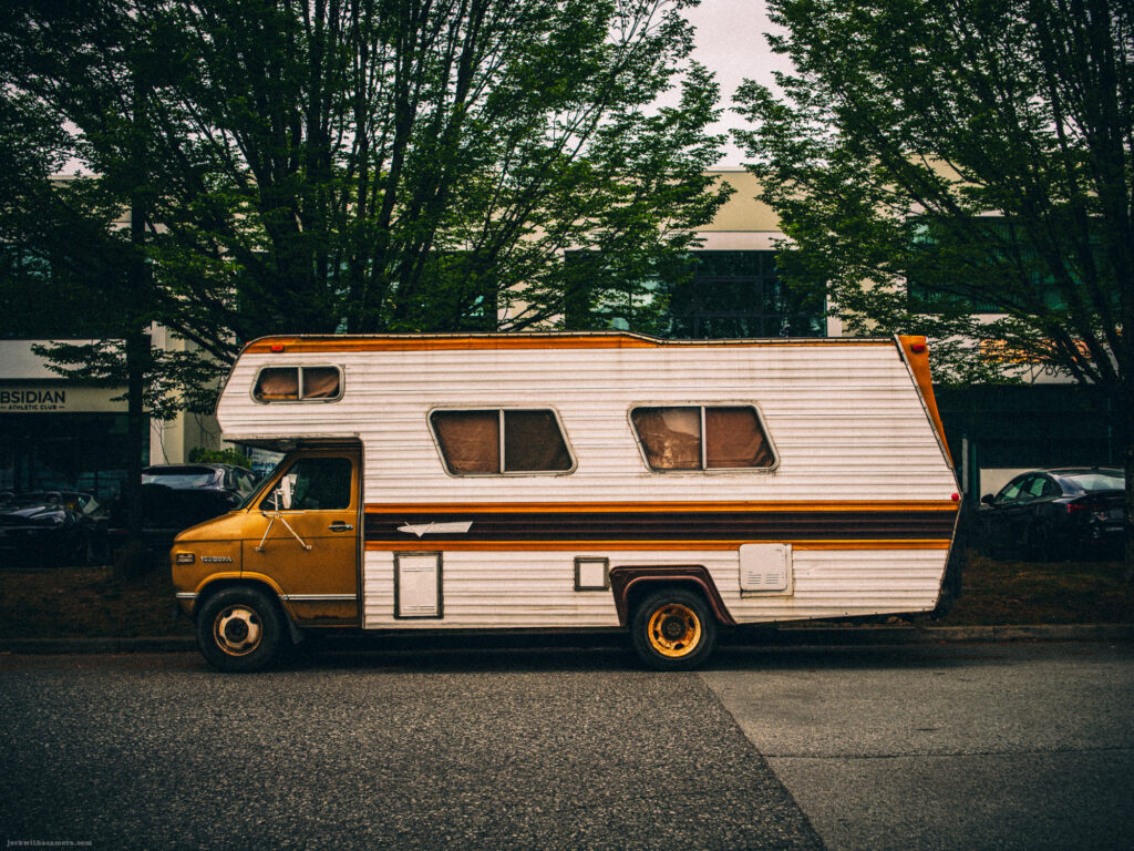 Vintage motorhome with orange and brown stripes parked on street