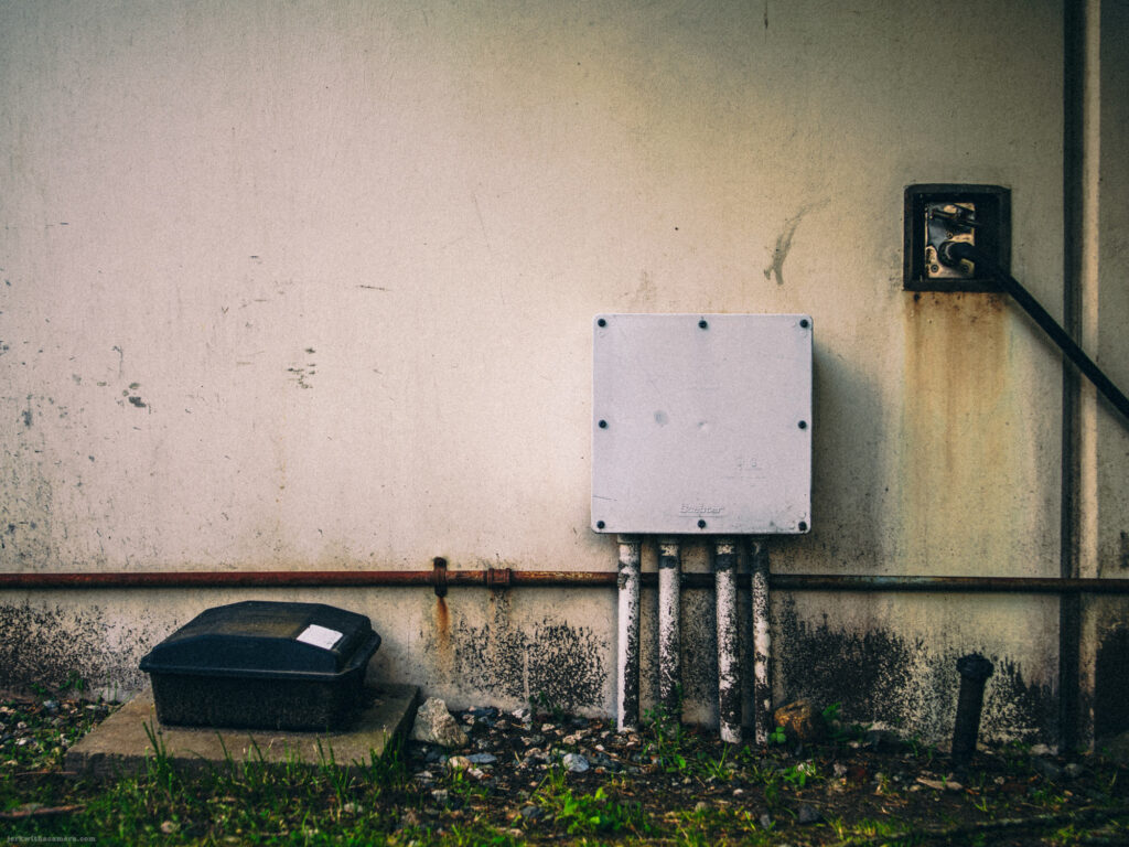 Electrical utility box and vent on stained wall