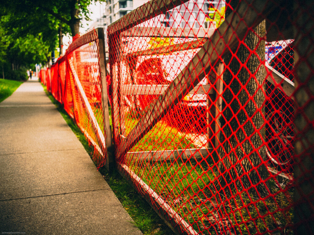 Orange mesh fencing around a sidewalk construction zone
