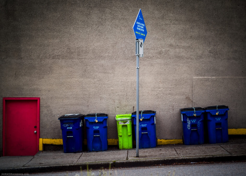 Recycling bins and red door beside concrete wall
