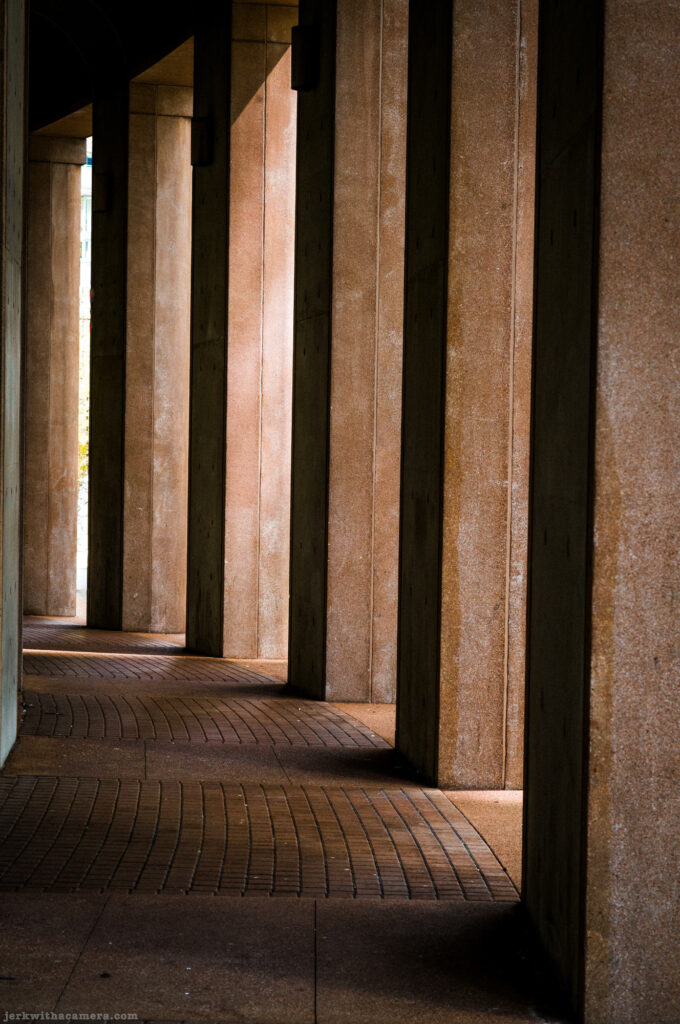 Shaded walkway with columns and brick pathway