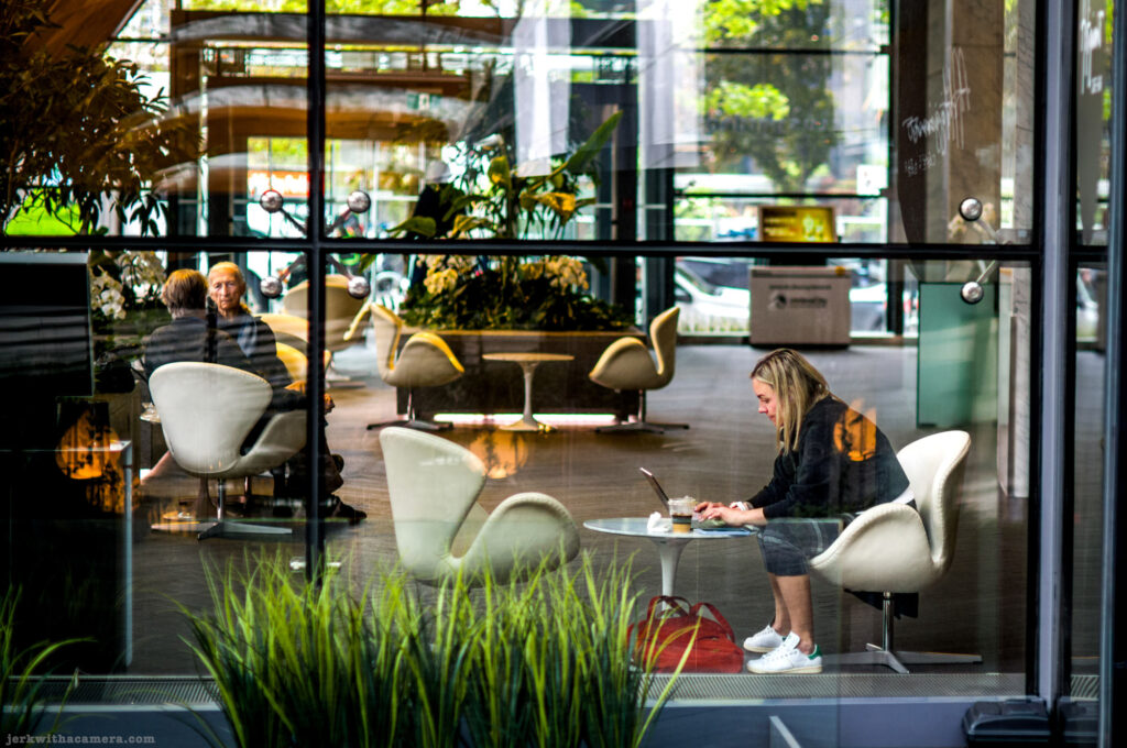 People inside a café viewed through glass with reflections