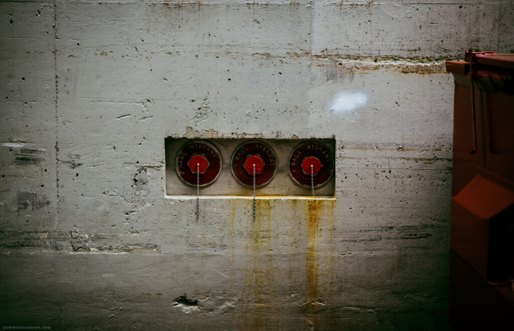 Three red wall hydrants mounted on concrete with yellow streaks