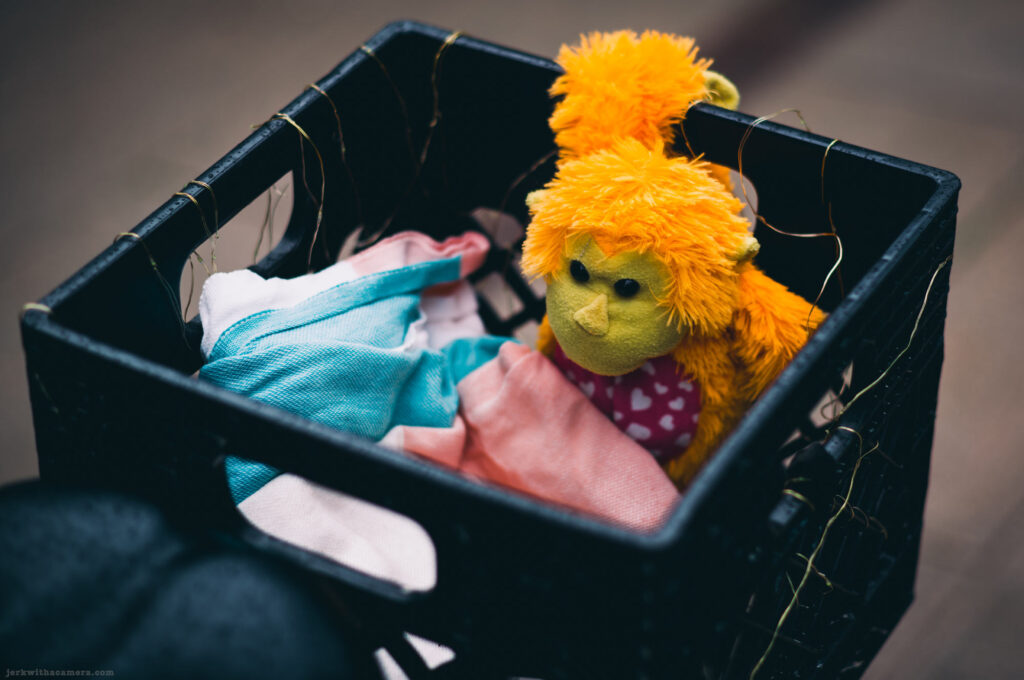 Yellow and orange stuffed toy monkey in a crate with fabric
