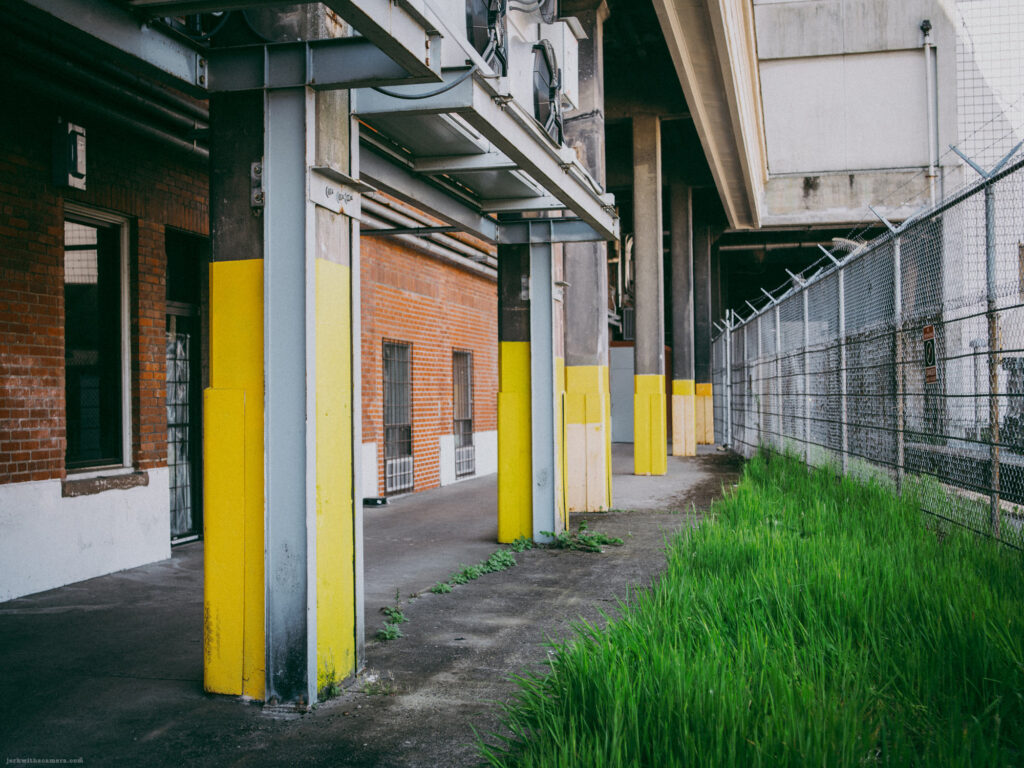 Back side of a brick warehouse with steel beams and yellow-painted columns