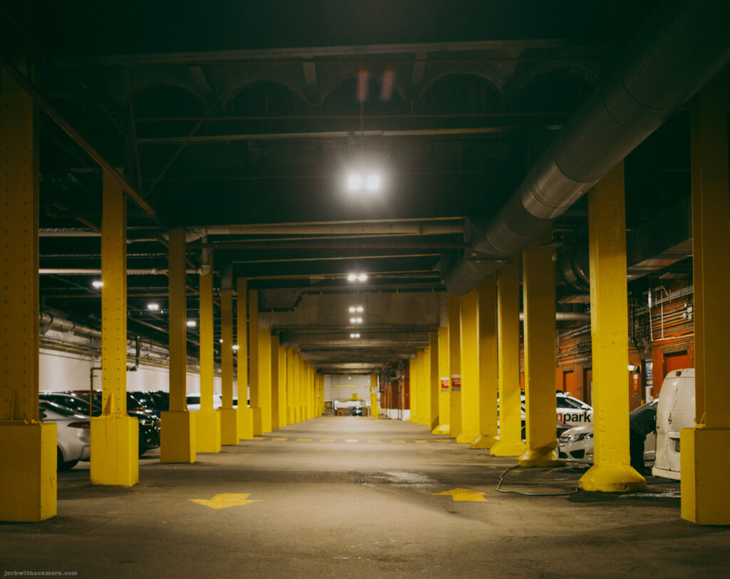 Yellow-painted columns along a concrete loading dock beside a chain-link fence