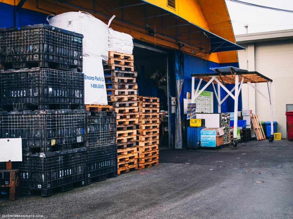 Industrial loading area with stacked pallets and plastic crates outside a warehouse in North Vancouver