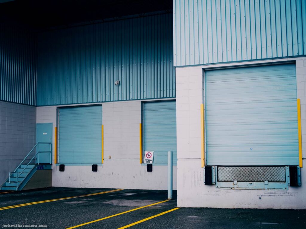 Two loading bay doors with stairs and yellow markings on asphalt.