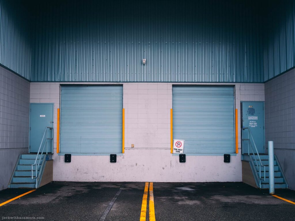 Two loading bay doors with stairs and yellow markings on asphalt.