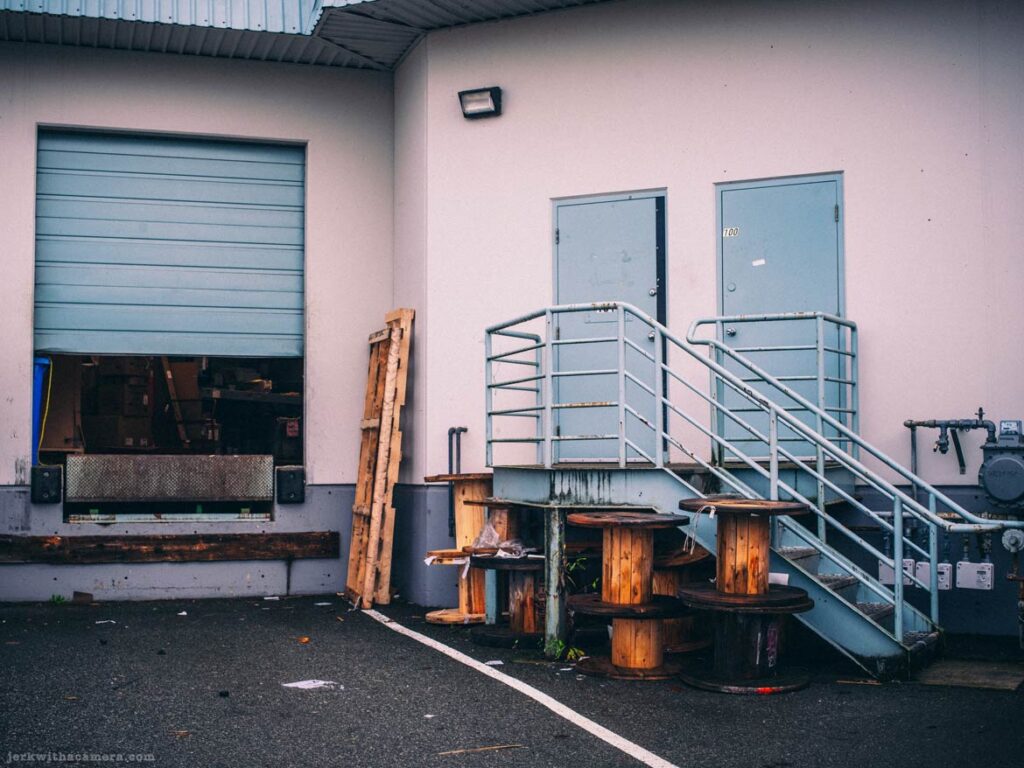 Two loading bay doors with stairs and yellow markings on asphalt.