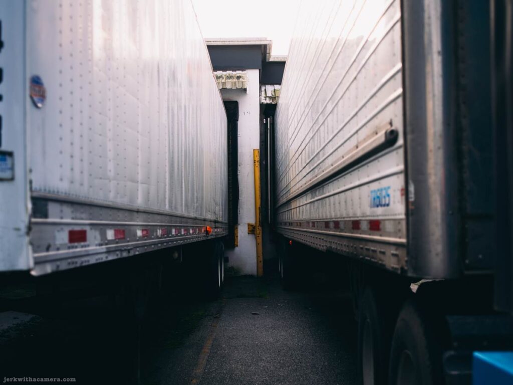 Narrow gap between two parked transport trailers at a loading dock in North Vancouver