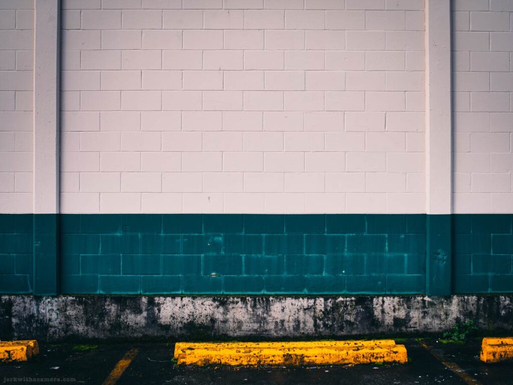 White brick wall with teal lower section and yellow parking stop at Lonsdale Quay
