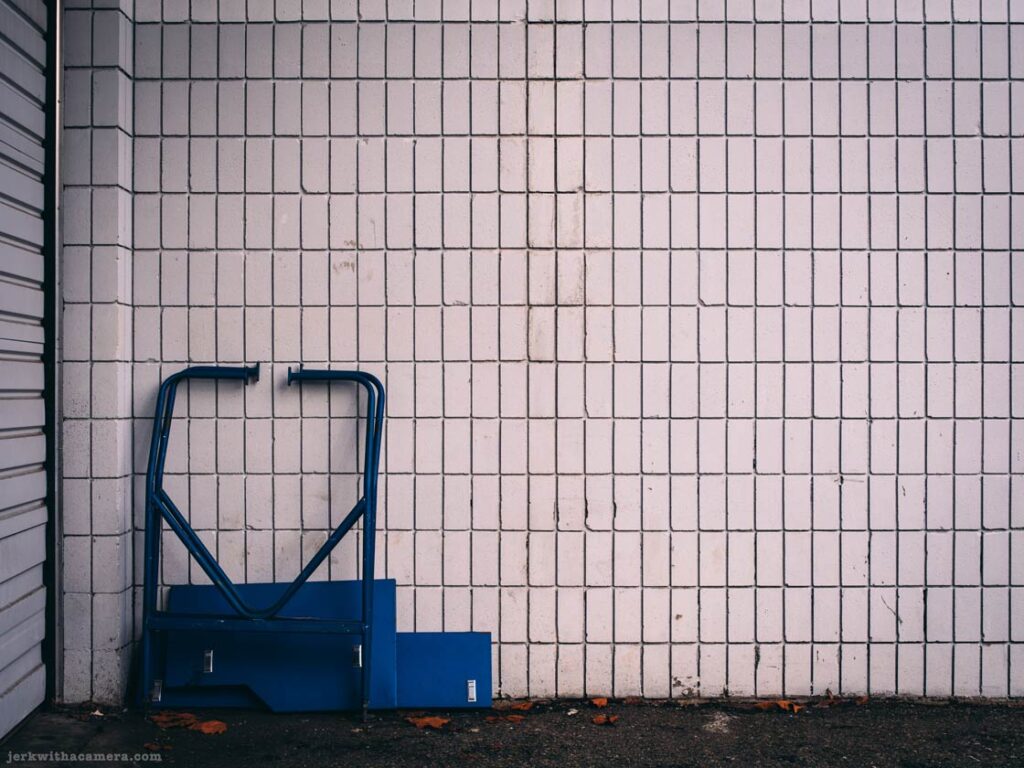 Blue metal cart leaning against a tiled wall beside a roll-up door in North Vancouver